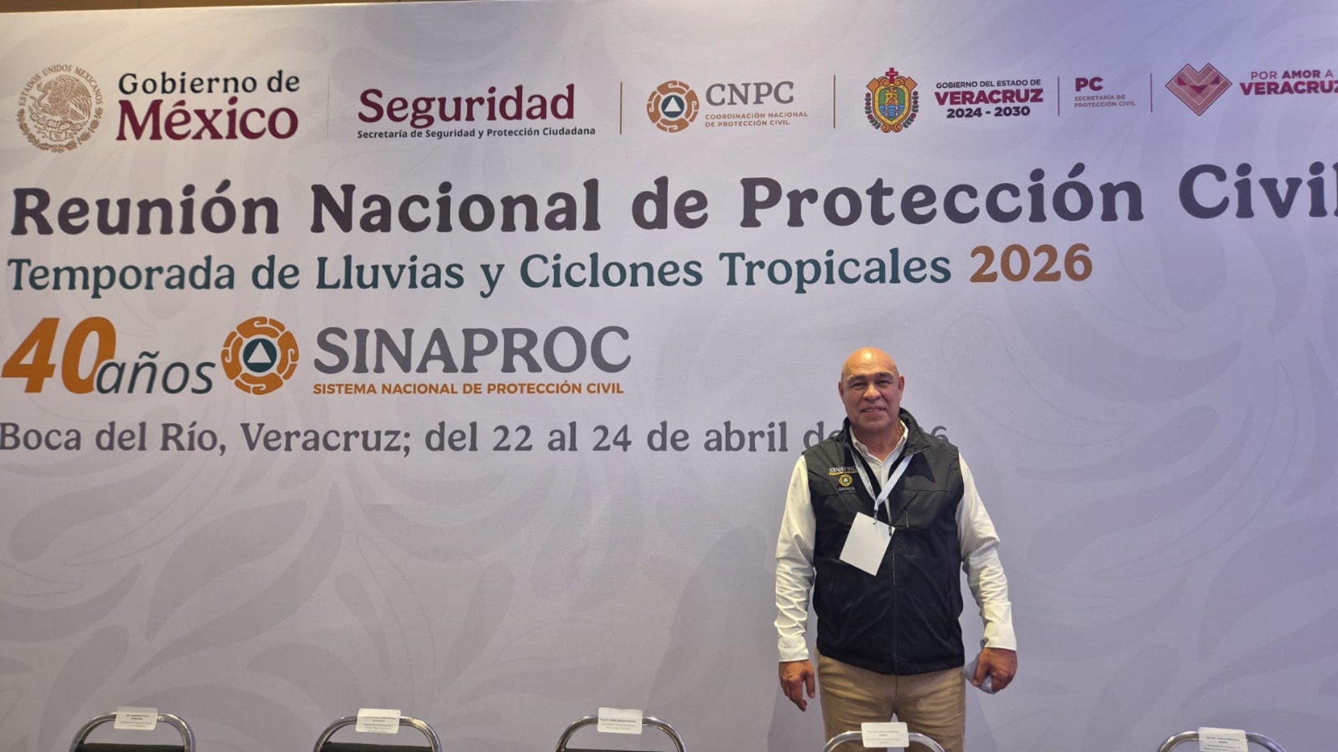 Manuel Maza, funcionario de Oaxaca, posa frente a la leyenda "Reunión Nacional de Protección Civil sobre la Temporada de Lluvias y Ciclones Tropicales 2026".