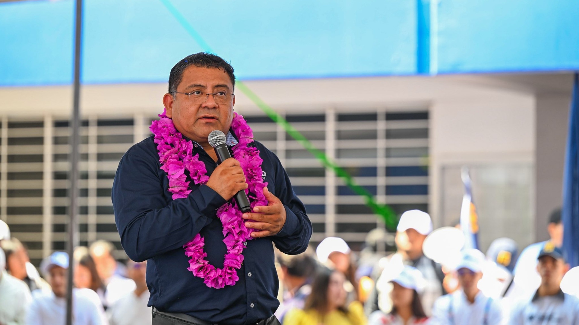 Farid Acevedo con camisa negra y un collar de flores en un evento público.