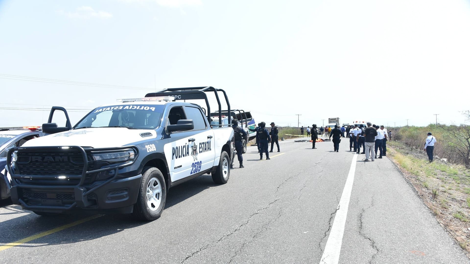 Patrullas de la policía de Oaxaca con varios agentes en un operativo sobre una carretera.