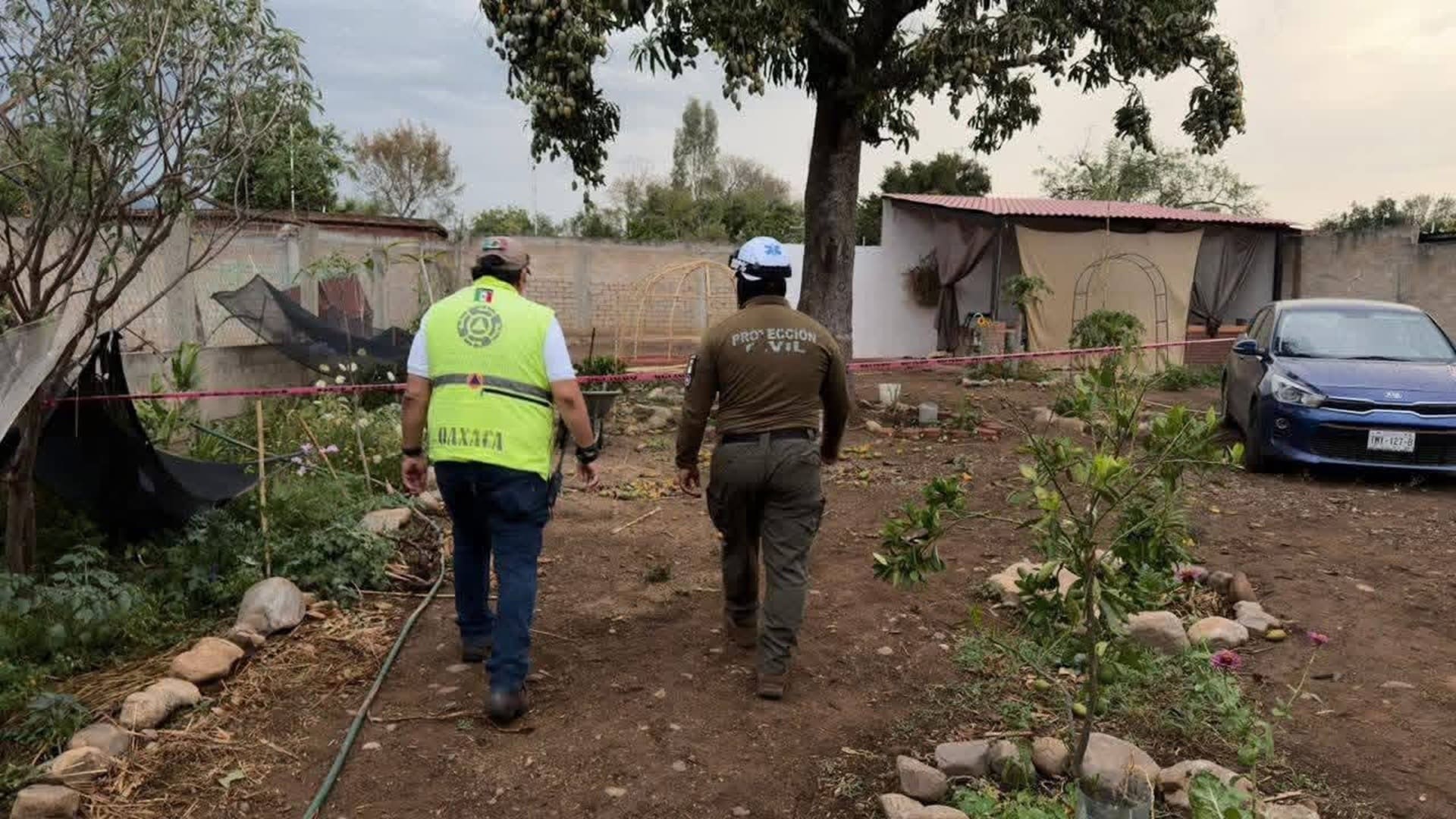 Dos personas, una con uniforme verde, caminan en un patio.