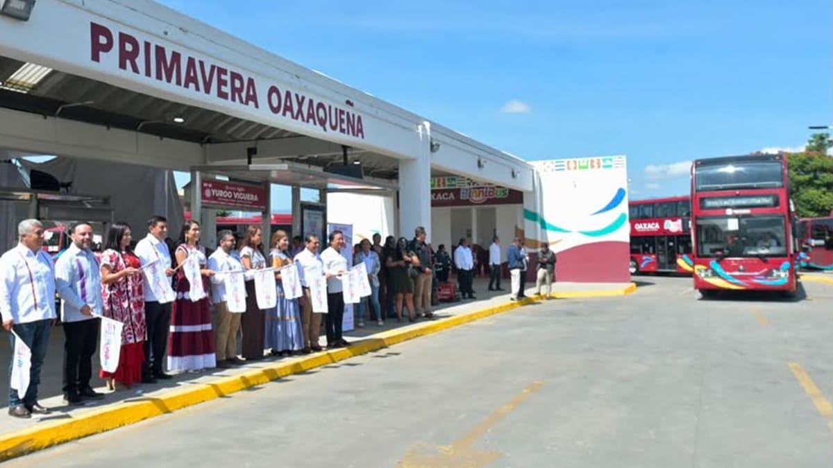 Personas con banderas blancas al paso de una unidad de BinniBus en Oaxaca