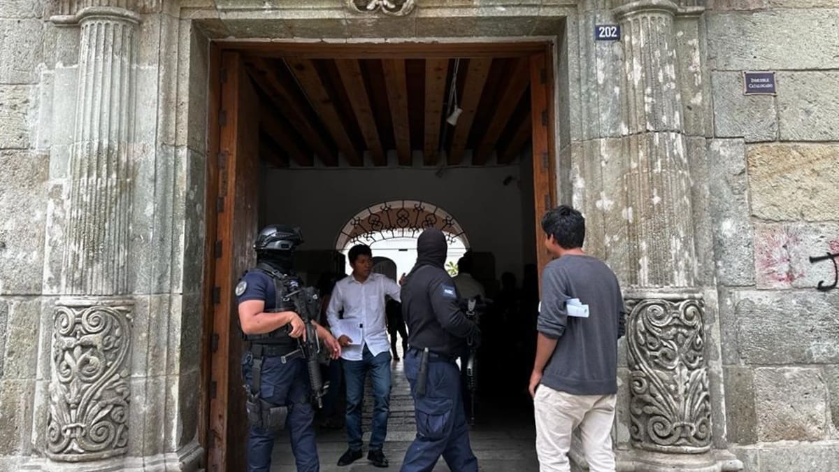 Policías y otros civiles en la entrada de un inmueble en Oaxaca