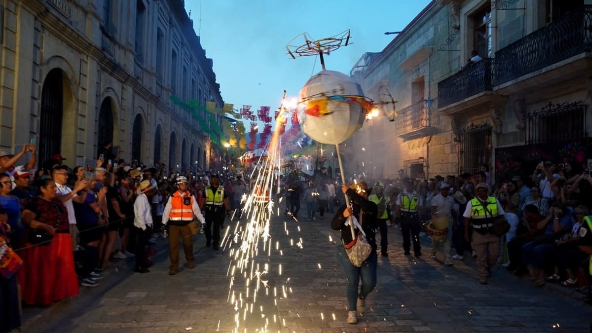 Imagen de la Calenda de las Cultura 2026 en el Centro Histórico de Oaxaca con un danzante cargando una farola y decenas de personas observando