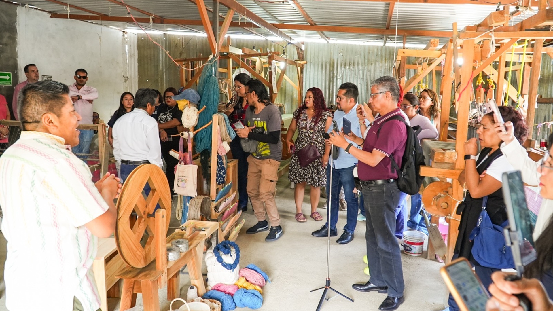 Varias personas reunidas en un cuarto donde sobresale un telar oaxaqueño.