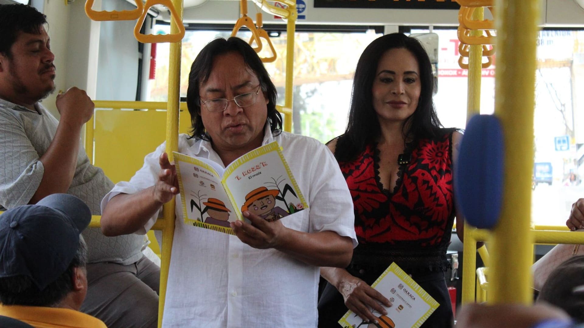 Víctor Cata en un BinniBus, leyendo un libro; se aprecian otros usuarios.