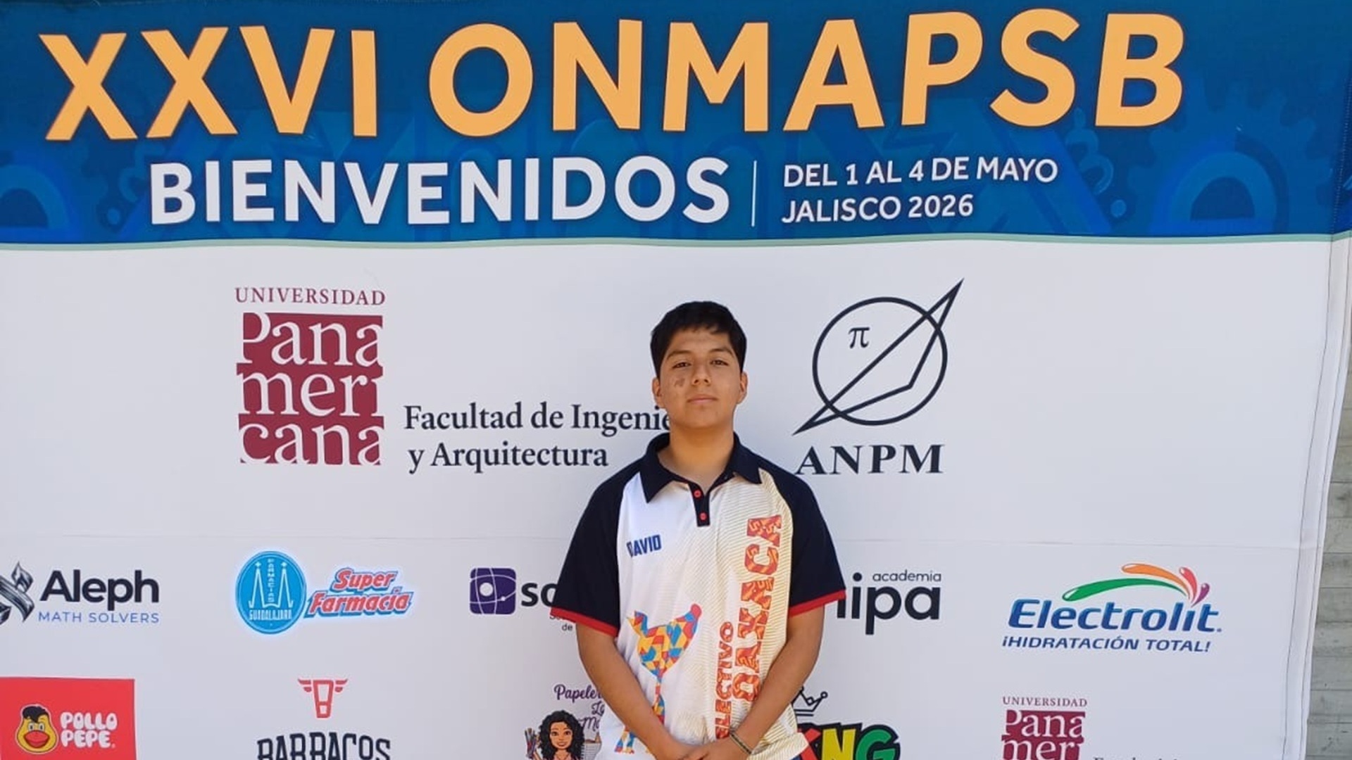 El estudiante Daniel Martínez posa frente a una lona en la que se lee ONMAPSB.