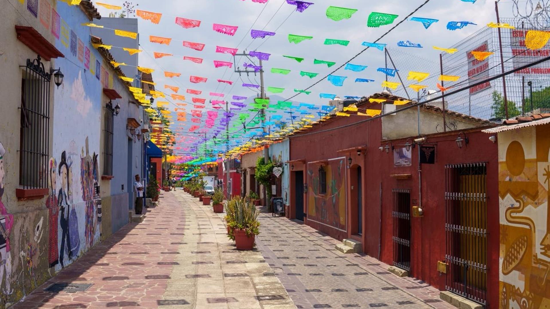 Calle empedrada del barrio Xochimilco en Oaxaca, adornada con papeles de colores.