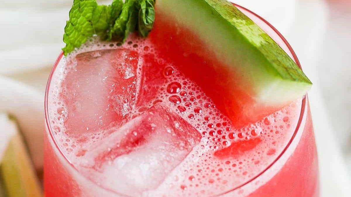 Vaso de agua de sandía con un pedazo de la fruta en el borde
