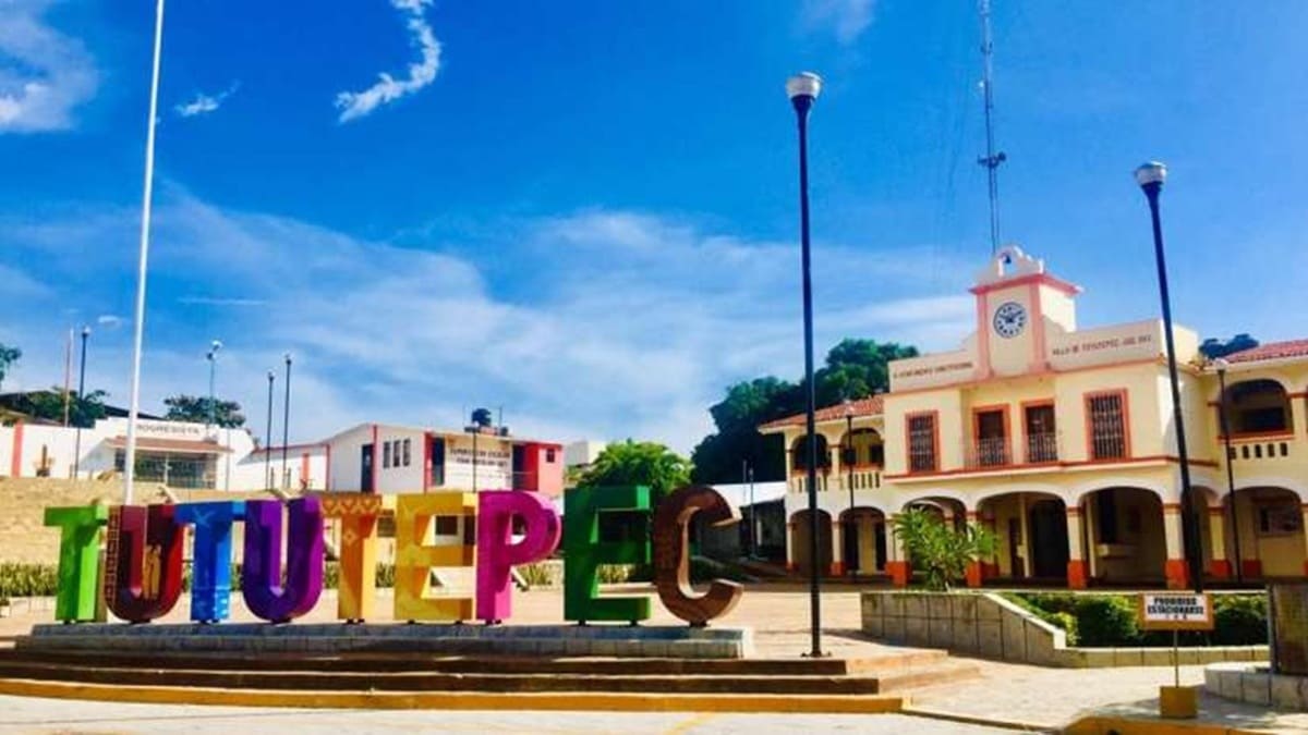 Fachada amarilla y rojo del Palacio Municipal de Villa de Tututepec, Oaxaca, atrás de un letrero monumental