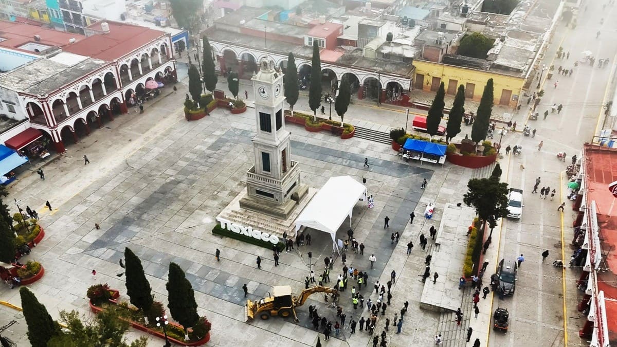 Vista aérea del Palacio Municipal de Tlaxiaco y su zócalo rodeado de árboles y un monumento con un reloj en el centro