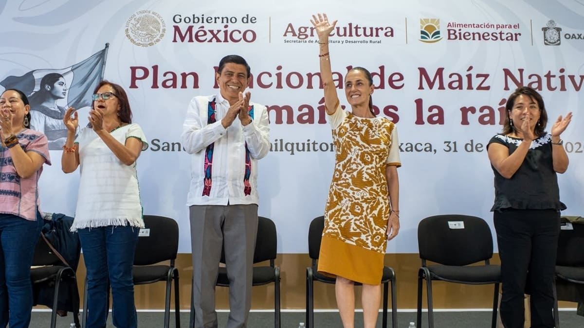 Claudia Sheinbaum con un vestido con adornos amarillos junto a Salomón Jara en un templete en Oaxaca