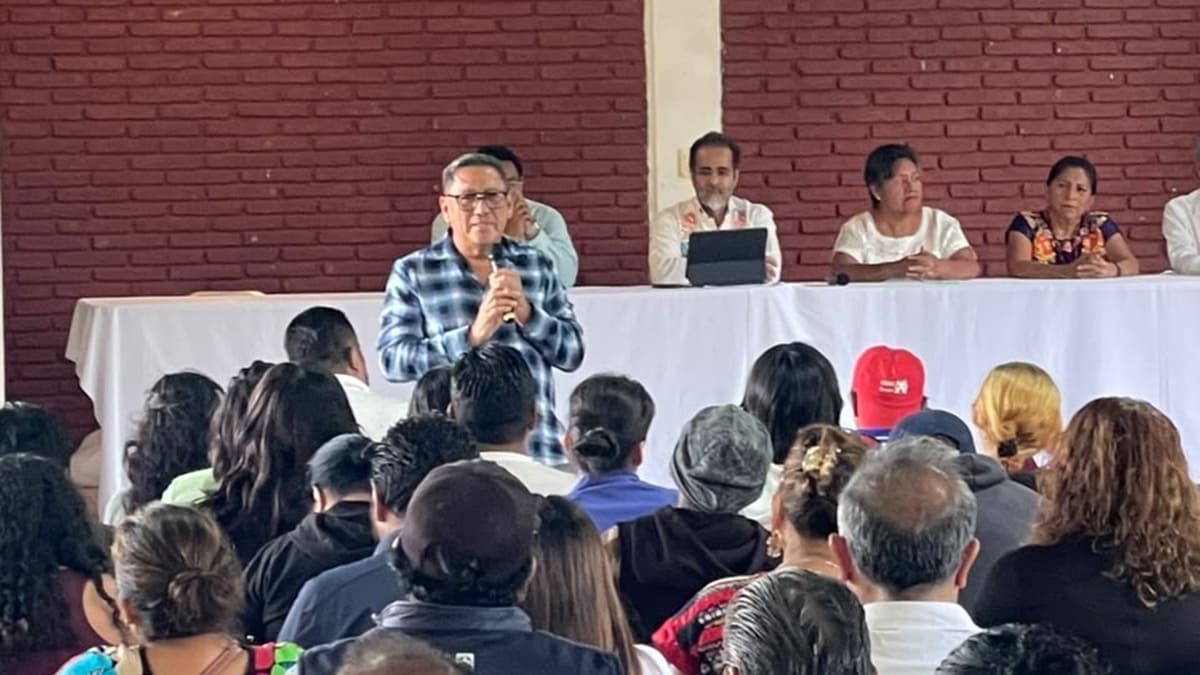 Domingo García habla frente a una multitud con René Bejarano sentado observando el momento