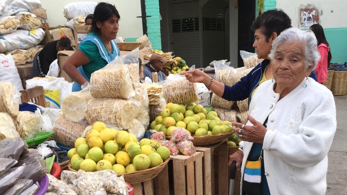 Una vendedora en el mercado de Miahuatlán de Porfirio Díaz comercia con dos personas adultas, entre limones, totopos y otras mercancías.