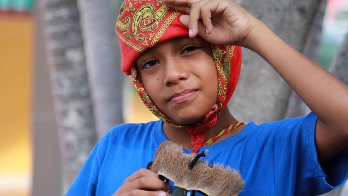 Joven afromexicano con una pañoleta en la cabeza y una máscara de madera en la mano