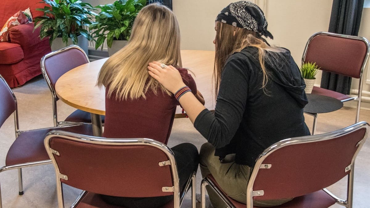 Dos mujeres conversando sentadas junto a una mesa