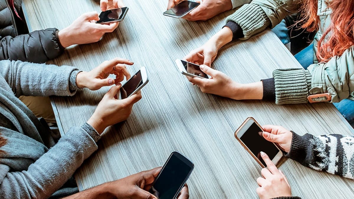 Las manos de varios jóvenes manipulando teléfonos celulares