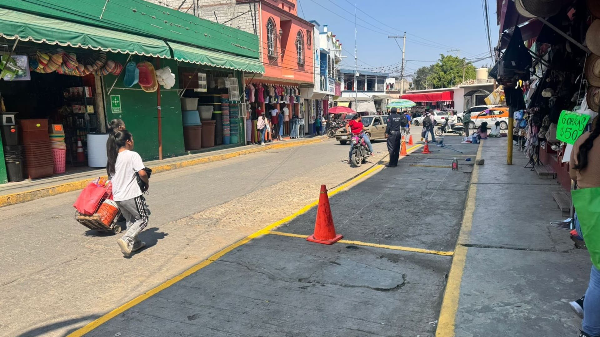 Una niña entre otras personas caminan por una calle céntrica en Miahuatlán de Porfirio Díaz.