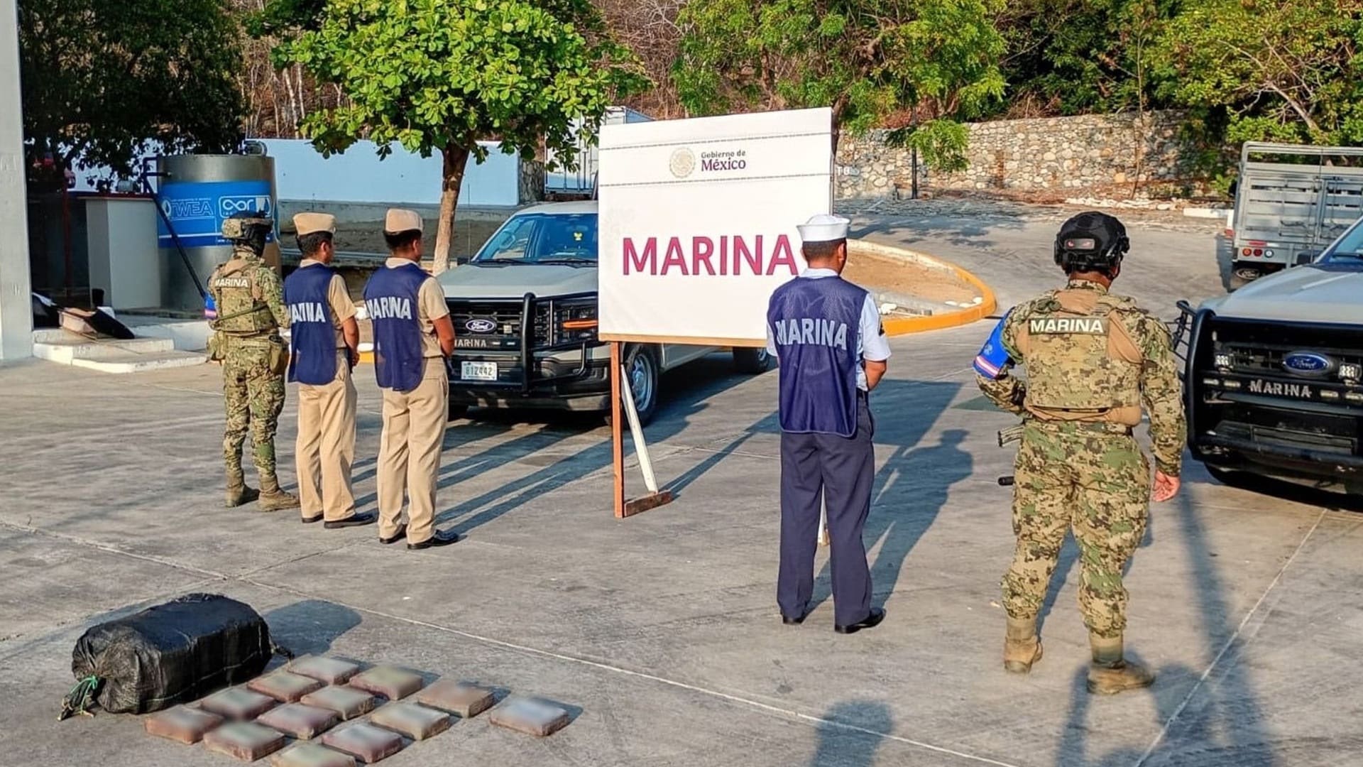 Elementos de Marina dando la espalda a la cámara y resguardando paquetes en el suelo.