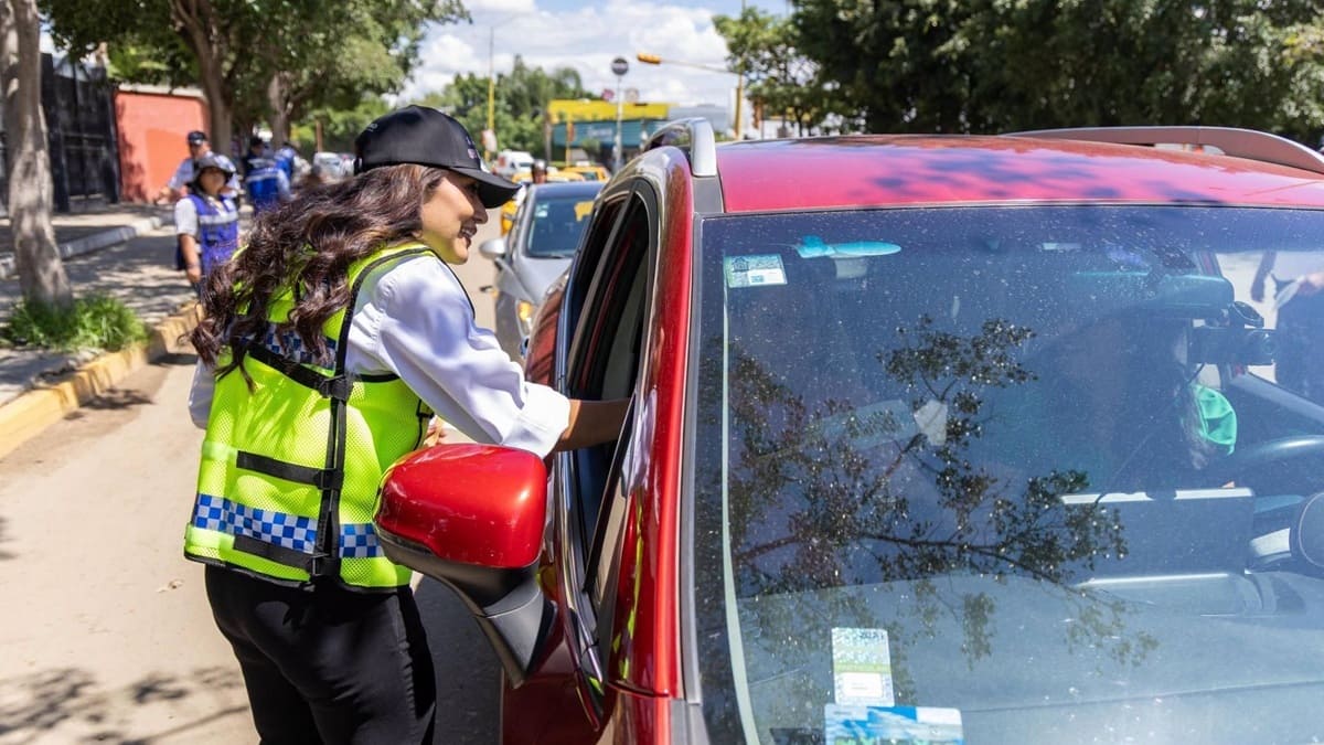 Una trabajadora de Semovi de Oaxaca con chaleco verde ofrece información a un conductor
